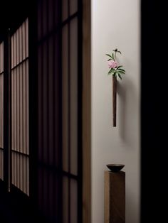 a cross hanging from the side of a wall next to a vase with flowers on it