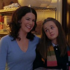 two women standing next to each other in front of an open refrigerator