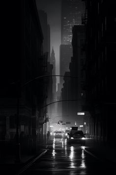 a black and white photo of a city street at night with cars driving down the road