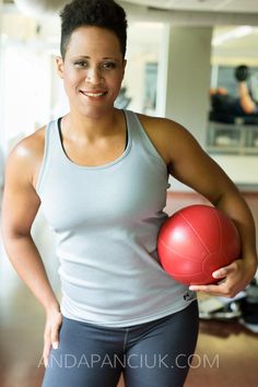 a woman is holding a red ball in her right hand and smiling at the camera