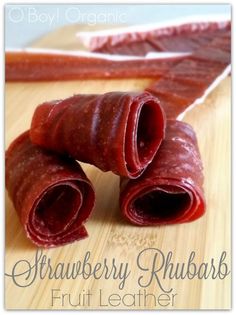 two pieces of raw meat sitting on top of a wooden cutting board with the words, strawberry rhubars fruit leather