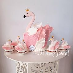 cupcakes with frosting in the shape of swans are on a cake stand