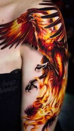 a woman with a tattoo on her arm that has a bird on it and flames in the background