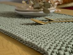 a close up of a place mat on a wooden table with flowers in the background