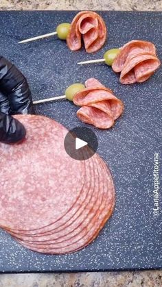 a cutting board topped with ham and olives