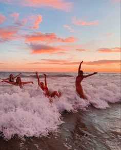 three women are in the water on their stomachs and arms up as they surf