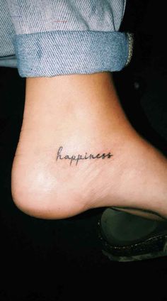 a person with a tattoo that says happiness on their foot