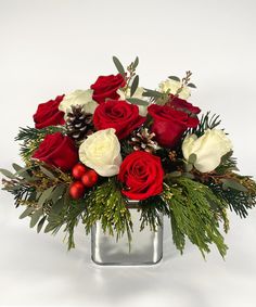 a bouquet of red and white roses in a silver vase with greenery on the side