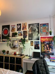 a bedroom with posters on the wall and a computer desk in front of it,