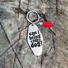 a keychain that says can i bring my dog? on it sitting on top of a piece of wood