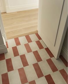 an orange and white checkered floor next to a tall door in a room with hardwood floors