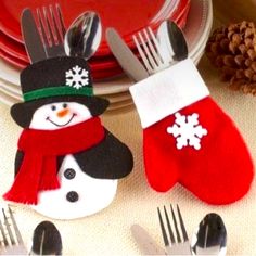 two snowman mittens sitting on top of a table next to forks and knives