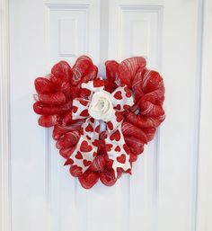 a red and white heart shaped wreath hanging on a door