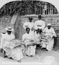 an old black and white photo of five people in front of a brick wall, holding baskets