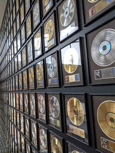 there are many records on the wall and one is in front of them with gold discs