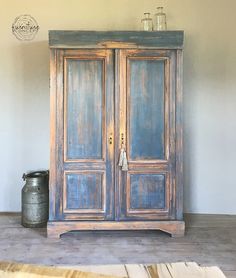 an old wooden armoire sitting on top of a floor next to a metal can