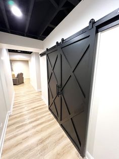 an empty room with white walls and wooden floors has a black sliding barn door on the wall