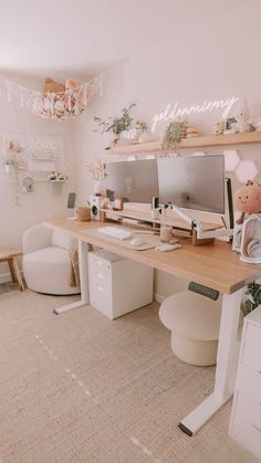 a desk with two computer monitors on it in front of a white couch and chair