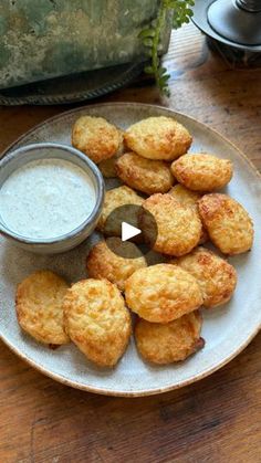 some fried food is on a white plate with a small bowl of ranch dressing next to it