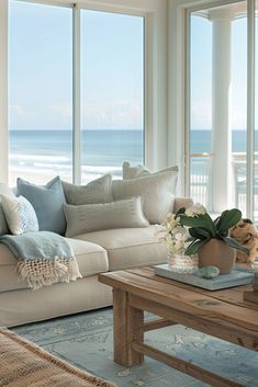 a living room filled with lots of furniture and large windows overlooking the ocean in front of it