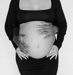 a pregnant woman with her hands on her belly, wearing a black top and skirt