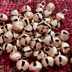 a pile of silver bells sitting on top of a red rug