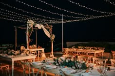 an outdoor dining area with tables and chairs set up for a wedding reception at night