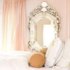 a teddy bear sitting on top of a bed next to a mirror and pillows in front of it