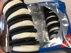 an oreo sandwich wrapped in black and white icing is being held by someone's hand