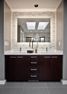 a bathroom with a large mirror above the sink and dark wood cabinetry on the wall