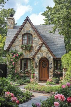 a stone house with flowers around the front door and windows on either side of it