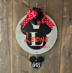 a mickey mouse sign hanging on the side of a wooden wall with a red bow