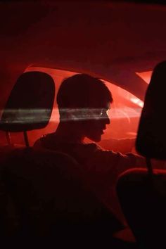 a man sitting in the passenger seat of a car with his headlight turned on