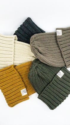 four different colors of knitted hats on a white background, one is green, the other is brown