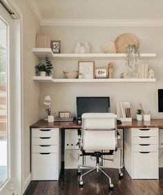 a desk with a computer on top of it in front of some shelves and drawers