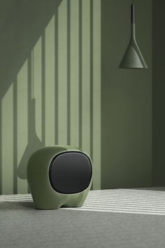 a green speaker sitting on top of a table next to a lamp