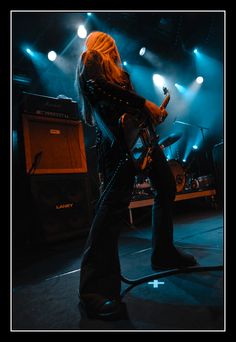 a woman with long blonde hair standing in front of a microphone and guitar on stage