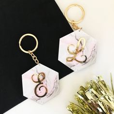 two marble key chains sitting on top of a black and white table next to some gold foil