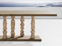 a wooden table sitting on top of a white floor next to a wall with mountains in the background