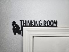 there is a black sign that says thinking room on the wall above a white door