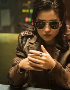 a woman wearing sunglasses is looking at her cell phone while sitting in a restaurant booth