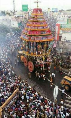 an elaborately decorated float in the middle of a crowded street with lots of people