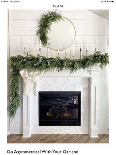 a white fireplace with greenery and candles on it, along with a wreath over the mantel