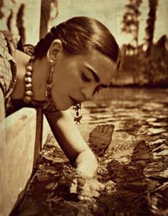 an old photo of a woman in the water with her hand over her face and looking down