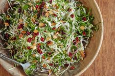 a wooden bowl filled with salad topped with shaved lettuce and cranberries