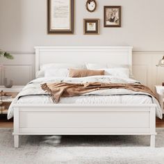 a white bed sitting in a bedroom next to two pictures on the wall above it