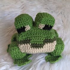 a crocheted green frog laying on top of a white furnishing with the words crochet pattern below it