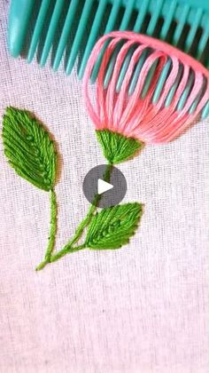 a pink and green flower sitting on top of a table next to a blue comb