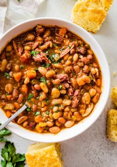 a white bowl filled with beans and bread on top of a marble counter next to some parsley