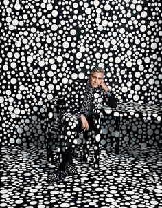 a man sitting on top of a bench in front of a black and white wall